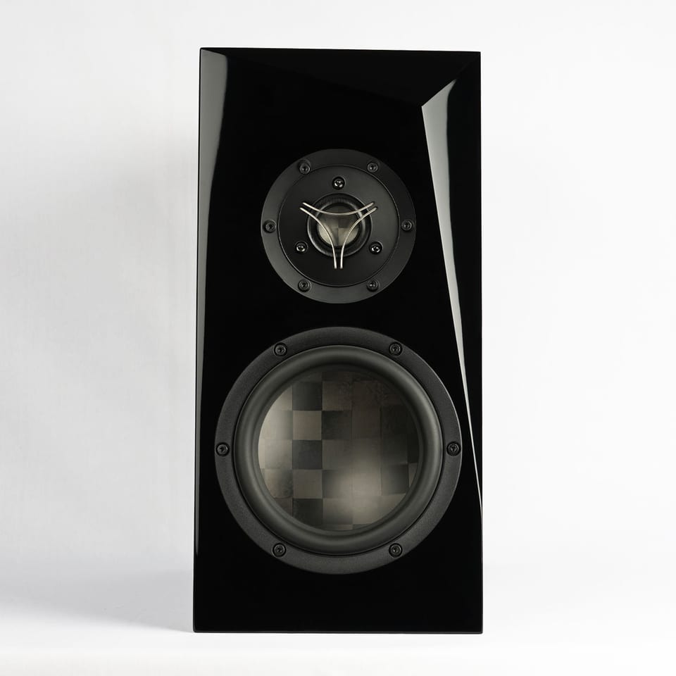 Ara TeXtreme bookshelf speaker in black gloss, straight on: a 29 mm TeXtreme dome tweeter on a black faceplate above a 6.5-inch midwoofer with a checkerboard spread-tow carbon cone.