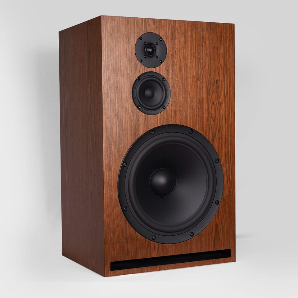 SB Acoustics Gema in wood veneer, angled view: tweeter, midrange, and large woofer above a front slot port