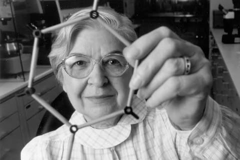 Stephanie Kwolek in a laboratory holding a ball-and-stick molecular model, black-and-white photo.