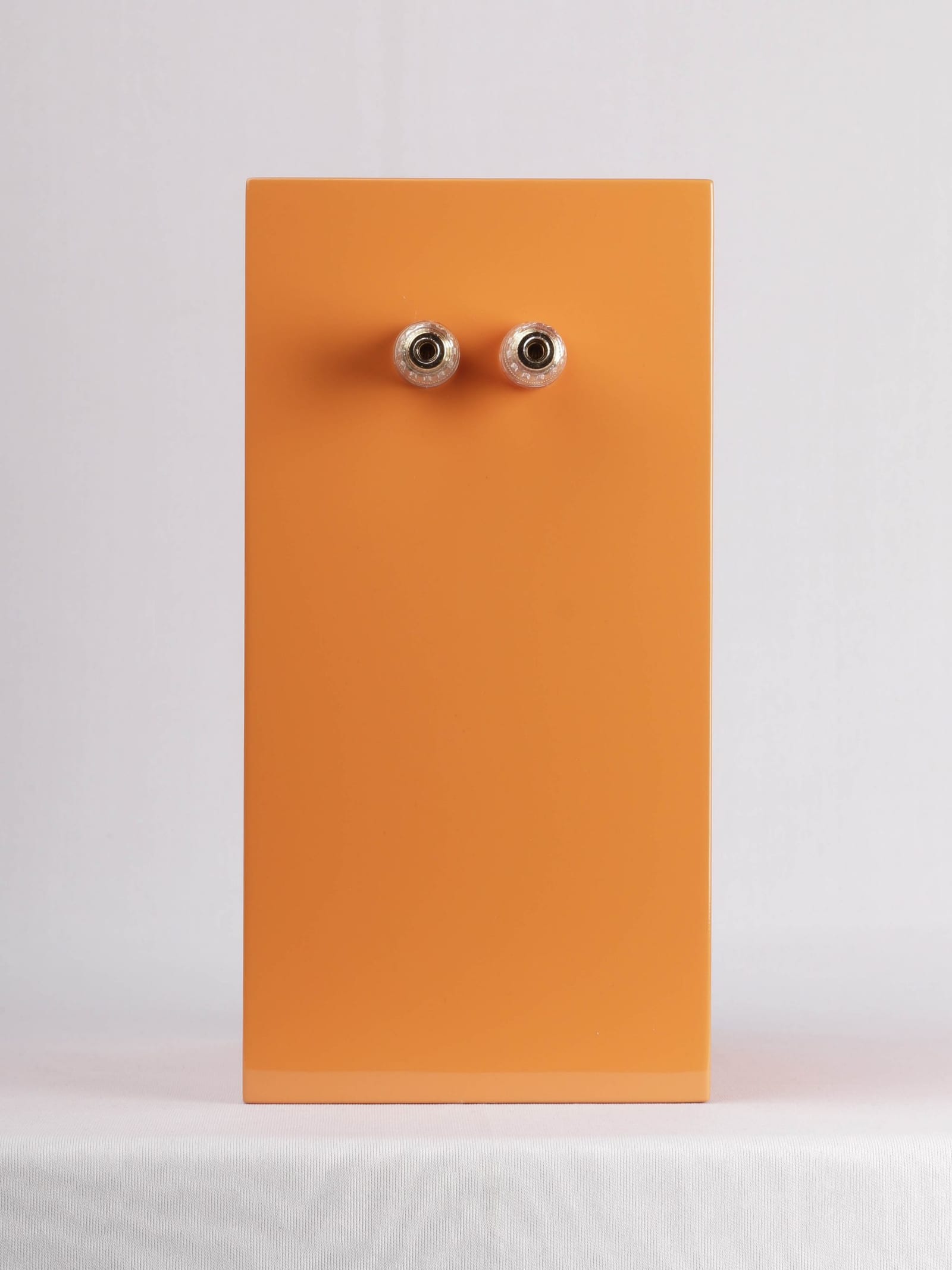 Rear of the Micro-C in orange gloss: two binding posts and an otherwise plain back panel, the port being front-firing.